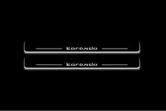 Two long door sill plates with Korando lettering and edges illuminated in white, straight-on view on a dark background.