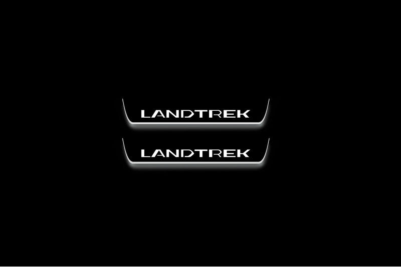 Two short door sill plates with Landtrek lettering and edges illuminated in white, straight-on view on a dark background.