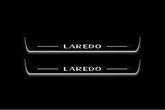 Two long door sill plates with Laredo lettering and edges illuminated in white, straight-on view on a dark background.