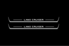 Two long door sill plates with Land Cruiser lettering and edges illuminated in white, straight-on view on a dark background.