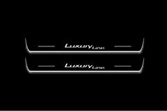 Two long door sill plates with Luxury Line lettering and edges illuminated in white, straight-on view on a dark background.