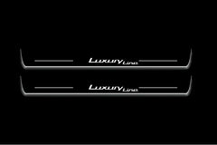 Two long door sill plates with Luxury Line lettering and edges illuminated in white, straight-on view on a dark background.