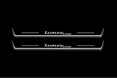 Two long door sill plates with Luxury Line lettering and edges illuminated in white, straight-on view on a dark background.