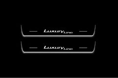 Two long door sill plates with Luxury Line lettering and edges illuminated in white, straight-on view on a dark background.