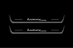 Two long door sill plates with Luxury Line lettering and edges illuminated in white, straight-on view on a dark background.