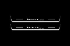 Two long door sill plates with Luxury Line lettering and edges illuminated in white, straight-on view on a dark background.
