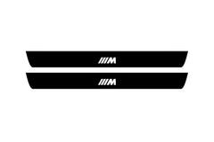 Catalog illustration of two black front door sill plates with ///M lettering.