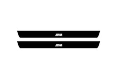 Catalog illustration of two black front door sill plates with ///M lettering.