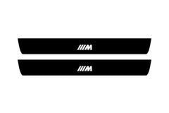 Catalog illustration of two black front door sill plates with ///M lettering.