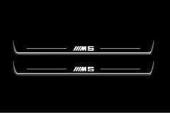 Two long door sill plates with M5 lettering and edges illuminated in white, straight-on view on a dark background.