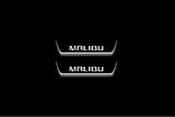 Two short door sill plates with Malibu lettering and edges illuminated in white, straight-on view on a dark background.
