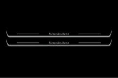 Two long door sill plates with Mercedes-Benz lettering and edges illuminated in white, straight-on view on a dark background.