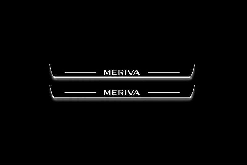 Two short door sill plates with Meriva lettering and edges illuminated in white, straight-on view on a dark background.