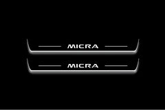 Two long door sill plates with Micra lettering and edges illuminated in white, straight-on view on a dark background.