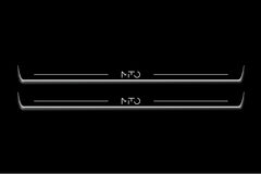 Two long door sill plates with MiTo lettering and edges illuminated in white, straight-on view on a dark background.
