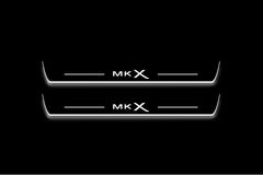 Two long door sill plates with MKX lettering and edges illuminated in white, straight-on view on a dark background.
