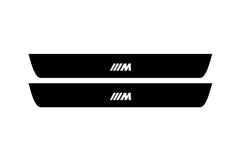 Catalog illustration of two black front door sill plates with ///M lettering.