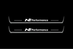 Two long door sill plates with N Performance lettering and edges illuminated in white, straight-on view on a dark background.