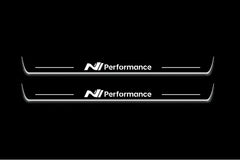Two long door sill plates with N Performance lettering and edges illuminated in white, straight-on view on a dark background.