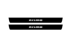 Catalog illustration of two black front door sill plates with Nismo lettering.