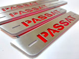 Close-up of bold red Passat lettering and horizontal slots on long and short silver-finished door sill plates.
