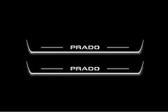 Two long door sill plates with Prado lettering and edges illuminated in white, straight-on view on a dark background.
