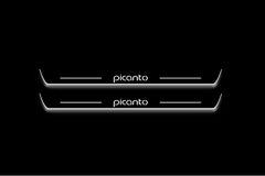Two long door sill plates with Picanto lettering and edges illuminated in white, straight-on view on a dark background.
