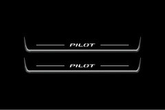 Two long door sill plates with Pilot lettering and edges illuminated in white, straight-on view on a dark background.