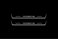 Two long door sill plates with Porsche lettering and edges illuminated in white, straight-on view on a dark background.