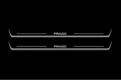 Two long door sill plates with Prado lettering and edges illuminated in white, straight-on view on a dark background.