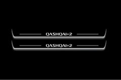 Two long door sill plates with Qashqai+2 lettering and edges illuminated in white, straight-on view on a dark background.