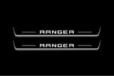 Two long door sill plates with Ranger in block lettering lettering and edges illuminated in white, straight-on view on a dark background.