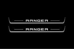 Two long door sill plates with Ranger in block lettering lettering and edges illuminated in white, straight-on view on a dark background.