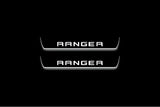 Two short door sill plates with Ranger in block lettering lettering and edges illuminated in white, straight-on view on a dark background.