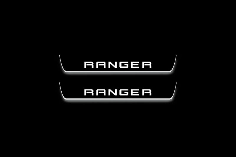 Two short door sill plates with Ranger in block lettering lettering and edges illuminated in white, straight-on view on a dark background.