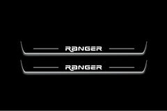 Two long door sill plates with Ranger in angular lettering lettering and edges illuminated in white, straight-on view on a dark background.