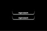 Two short door sill plates with Ranger in angular lettering lettering and edges illuminated in white, straight-on view on a dark background.