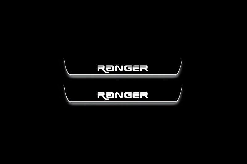Two short door sill plates with Ranger in angular lettering lettering and edges illuminated in white, straight-on view on a dark background.