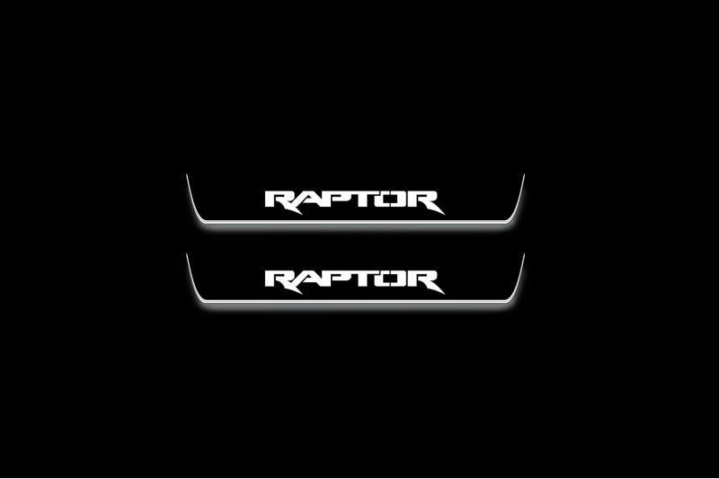 Two short door sill plates with Raptor lettering and edges illuminated in white, straight-on view on a dark background.