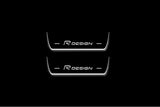 Two short door sill plates with R Design lettering and edges illuminated in white, straight-on view on a dark background.