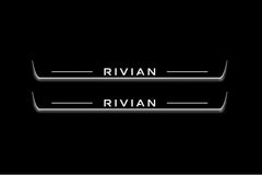 Two long door sill plates with Rivian lettering and edges illuminated in white, straight-on view on a dark background.