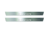 Two long silver-finished door sill plates with Rivian with diamond emblems lettering on a light background, straight-on view.