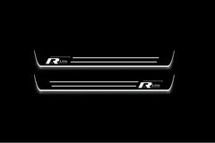 Two long door sill plates with R-Line emblems and horizontal stripes lettering and edges illuminated in white, straight-on view on a dark background.