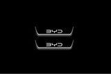 Two short door sill plates with BYD lettering and edges illuminated in white, straight-on view on a dark background.