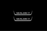 Two short door sill plates with Sealion 7 lettering and edges illuminated in white, straight-on view on a dark background.