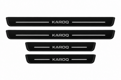 Catalogue illustration of two long front and two shorter rear black Matte PRO door sill plates with illuminated KAROQ lettering and straight top lines; edges unlit. Exact Karoq NU7 dimensions are selected for the vehicle.