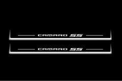 Two long door sill plates with Camaro SS lettering and edges illuminated in white, straight-on view on a dark background.