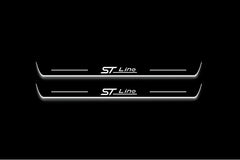 Two long door sill plates with ST Line lettering and edges illuminated in white, straight-on view on a dark background.