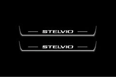 Two short door sill plates with Stelvio lettering and edges illuminated in white, straight-on view on a dark background.