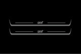 Two long door sill plates with STI lettering and edges illuminated in white, straight-on view on a dark background.